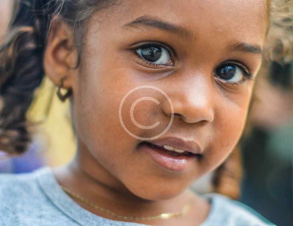 صورة مخزنة محمية بحقوق نشر لوجه طفلة ترتدي قرطاً بعدسة مقربة | Copyright-watermarked stock close-up of a child's face wearing an earring