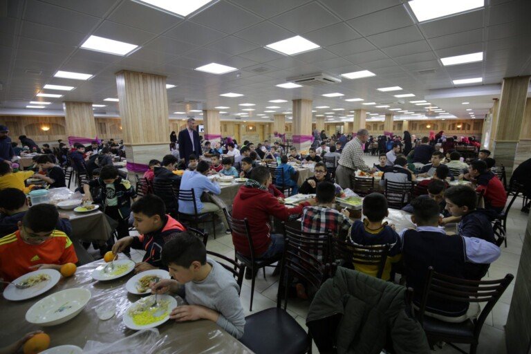 طلاب يتناولون الطعام داخل قاعة طعام كبيرة ضمن مبرة الإمام الخوئي في لبنان | Students having meals inside a large dining hall at Imam Al-Khoei Institution in Lebanon