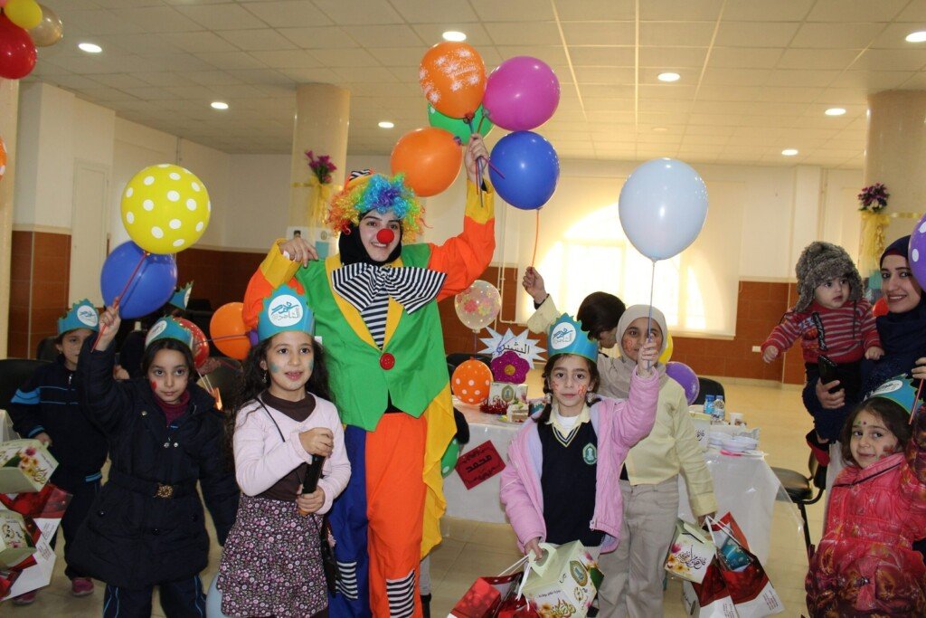أطفال في مبرّة الحوراء (ع) يشاركون في فعالية ترفيهية مع مهرج وبالونات ملونة | Children at Al Hawraa Care Institution participating in a recreational event with a clown and colorful balloons