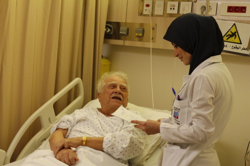 ممرضة تطمئن على مريض مسن في غرفته بمستشفى بهمن | A nurse checking on an elderly patient in his room at Bahman Hospital