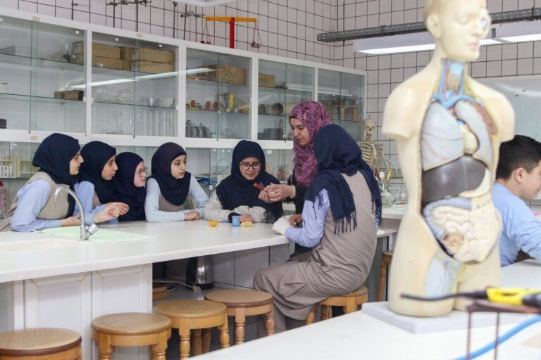معلمة وطالبات يشاركن في نشاط عملي داخل المختبر العلمي في مدرسة الإمام الحسين (ع) في لبنان | Teacher and students participating in a hands-on activity in the science lab at Al Imam Al Hussein (A) School in Lebanon