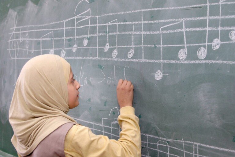 طالبة تكتب رموزاً موسيقية على السبورة في مدرسة الإمام الحسين (ع) في لبنان | Student drawing musical notes on a blackboard at Al Imam Al Hussein (A) School in Lebanon