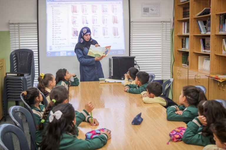 معلمة تقرأ كتاباً للطلاب داخل مكتبة مدرسة الإمام الحسين (ع) في لبنان | Teacher reading a book to students inside the library at Al Imam Al Hussein (A) School in Lebanon