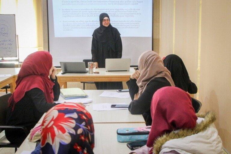 مدربة تحاضر أمام متدربات حول نظريات النمو المعرفي في مركز سراج | A trainer lecturing participants on cognitive development theories at Siraj Center
