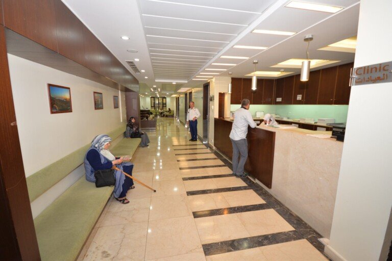 ممر العيادات الخارجية بمقاعد الانتظار ومكتب الاستقبال في مستشفى بهمن | The outpatient clinics corridor with waiting seats and reception desk at Bahman Hospital