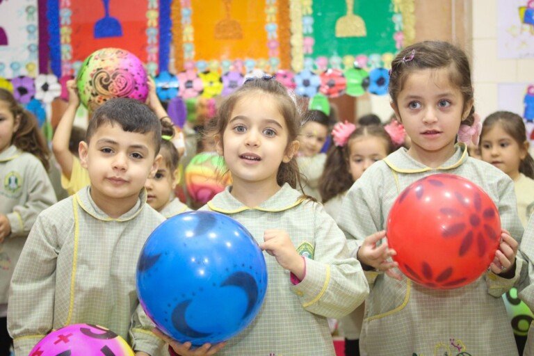 أطفال في صف مدرسي يشاركون في نشاط ترفيهي مع بالونات ملونة داخل ثانوية المجتبى | Children in a classroom participating in a recreational activity with colorful balloons at Al Mujtaba School