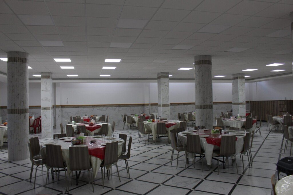 قاعة كبيرة تحتوي طاولات مرتبة لتقديم الطعام ضمن مبرة الإمام الرضا (ع) في لبنان | Large hall with arranged dining tables at Imam Al-Ridha Institution in Lebanon