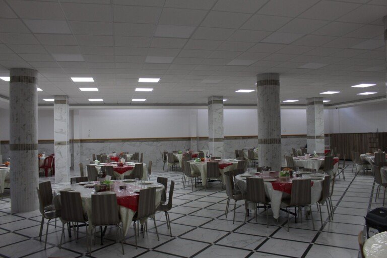 قاعة كبيرة تحتوي طاولات مرتبة لتقديم الطعام ضمن مبرة الإمام الرضا (ع) في لبنان | Large hall with arranged dining tables at Imam Al-Ridha Institution in Lebanon