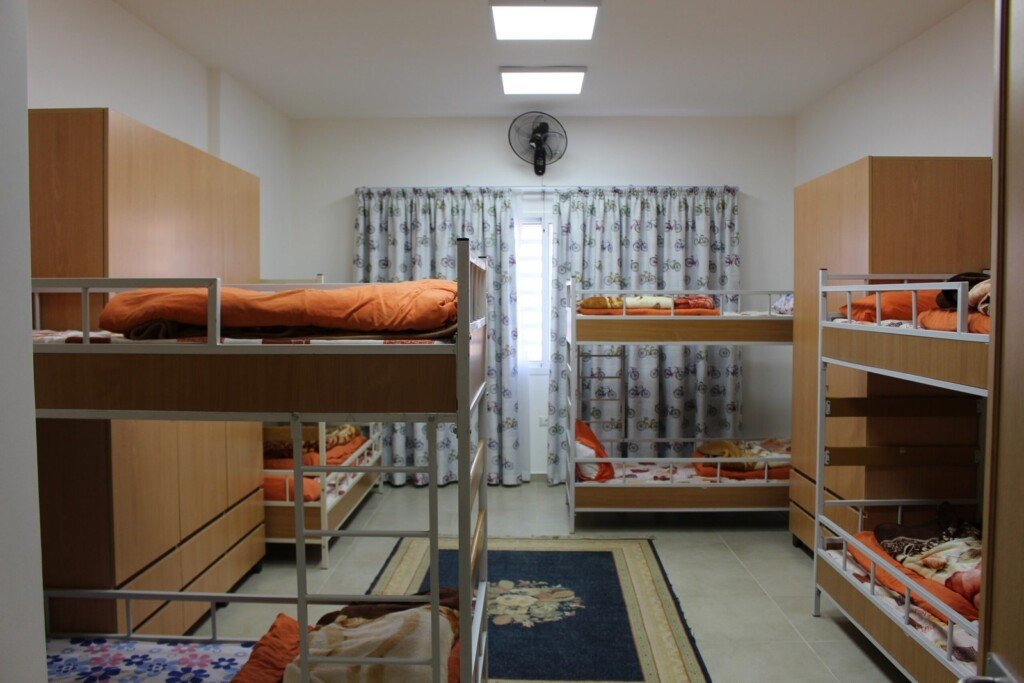 غرفة تحتوي أسرّة طابقية مرتبة داخل سكن طلابي في مبرة الإمام الرضا (ع) في لبنان | Room with arranged bunk beds inside a student dormitory at Imam Al-Ridha Institution in Lebanon