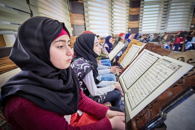 طالبات يقرأن القرآن الكريم في حلقة تعليمية بإشراف تربوي ضمن البرامج التعليمية في مبرة النبي إبراهيم (ع) | Female students reading the Quran in an educational study circle under supervision at Al Mabarrat Association programs