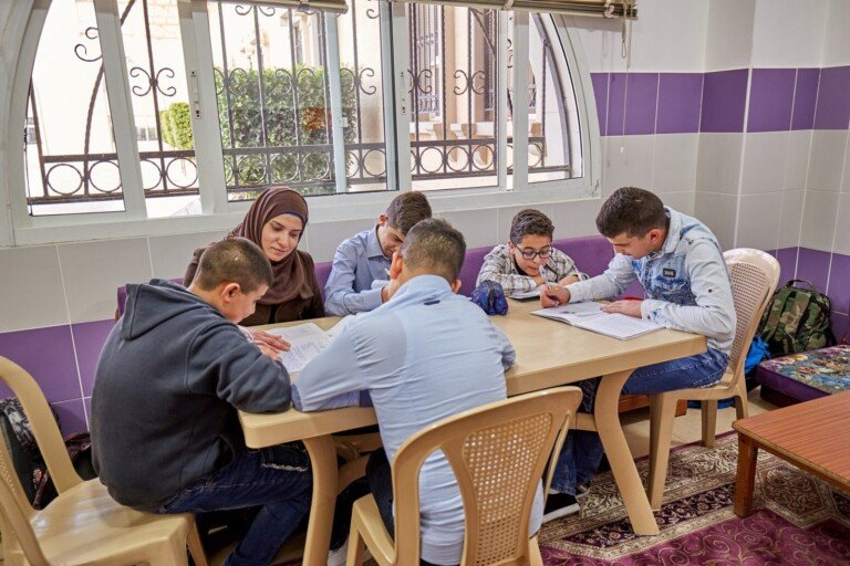 معلمة تشرف على مجموعة طلاب أثناء الدراسة داخل غرفة صفية ضمن البرامج التعليمية في مبرة النبي إبراهيم (ع) | A teacher supervising students during a study session inside a classroom at Al Mabarrat Association educational programs