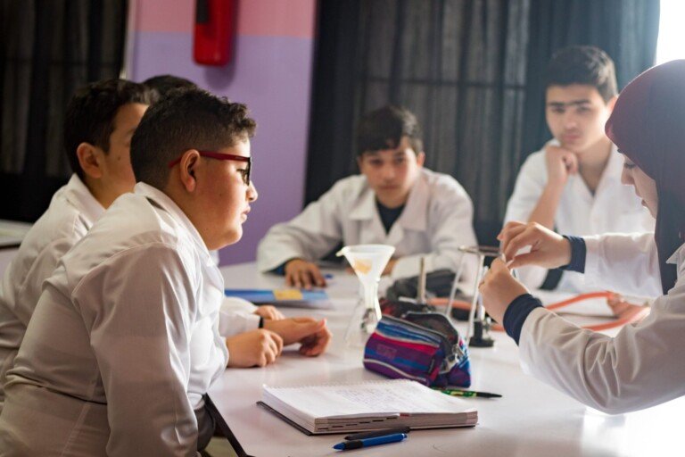 طلاب يشاركون في تجربة علمية داخل مختبر العلوم باستخدام أدوات مخبرية | Students conducting a science experiment in a laboratory using lab equipment