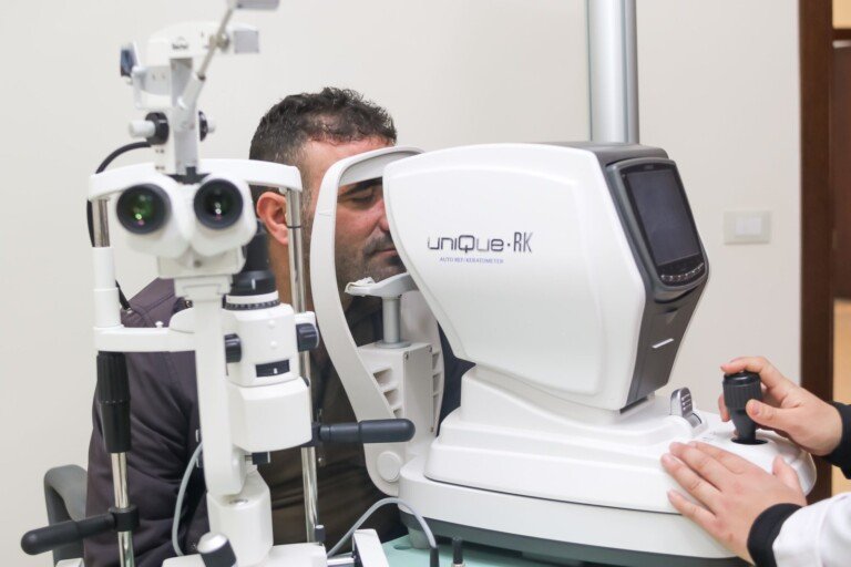 رجل يخضع لفحص النظر بجهاز قياس انكسار العين في مركز المصطفى الصحي الاجتماعي | A man undergoing an eye exam with an auto-refractometer at Al-Mustafa Social Health Center