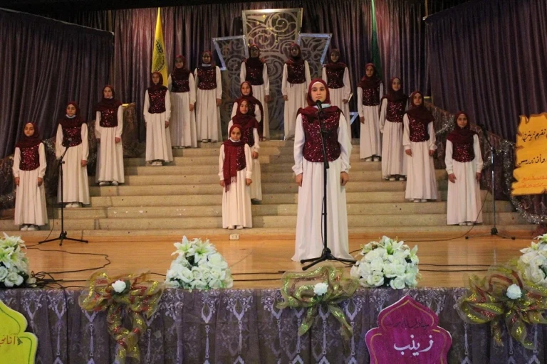 طلاب يؤدون عرضًا إنشاديًا على مسرح داخل مبرّة الإمام الخوئي في لبنان ضمن نشاط ثقافي وتربوي | Students performing a choir presentation on stage at Imam Al-Khoei Care Institution in Lebanon within a cultural and educational activity