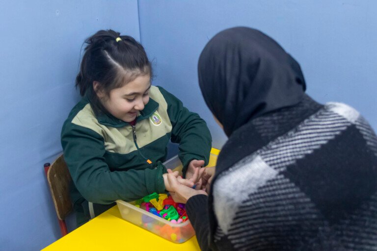 تلميذة تعمل مع اختصاصية على صندوق أحرف ملونة في مركز الهادي HDIC | A pupil working with a specialist on a colored-letters box at Al-Hadi Diagnostic Center HDIC