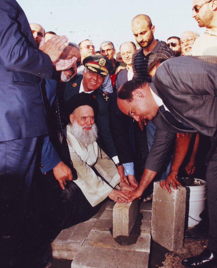 صورة تاريخية لمؤسس جمعية المبرات يضع حجر الأساس محاطاً بالرجال | A historical photo of the Al-Mabarrat founder laying a foundation stone surrounded by men